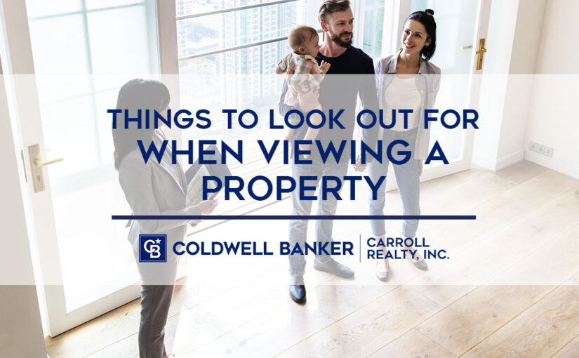 "Things To Look Out For When Viewing A Property" text over picture of family viewing a property with a real estate agent